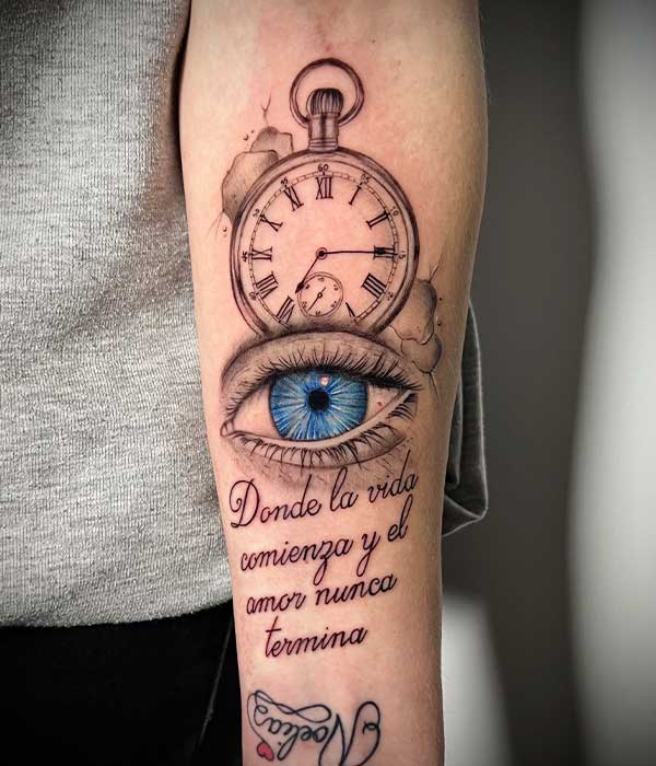 Tatuaje en el brazo de una brújula, ojo a color y frase por De la Rocha Tattoo en Cartagena