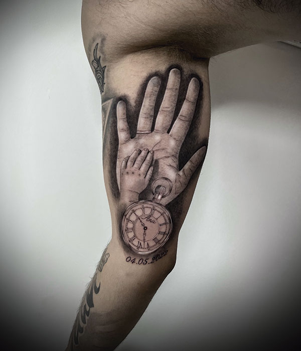 tatuaje manos de papa e hijo entrelazadas en negro con fecha de nacimiento y reloj con la hora. De la Rocha Tattoo Cartagena, Murcia