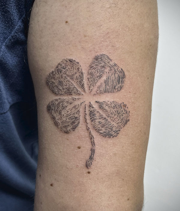 Tatuaje trebol de la suerte hecho con huellas digitles en el brazo en negro